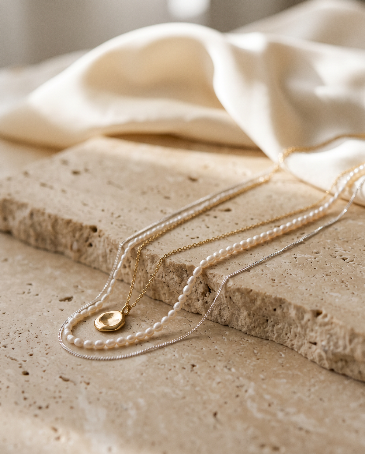 Tess & Mae Necklaces on warm beige travertine